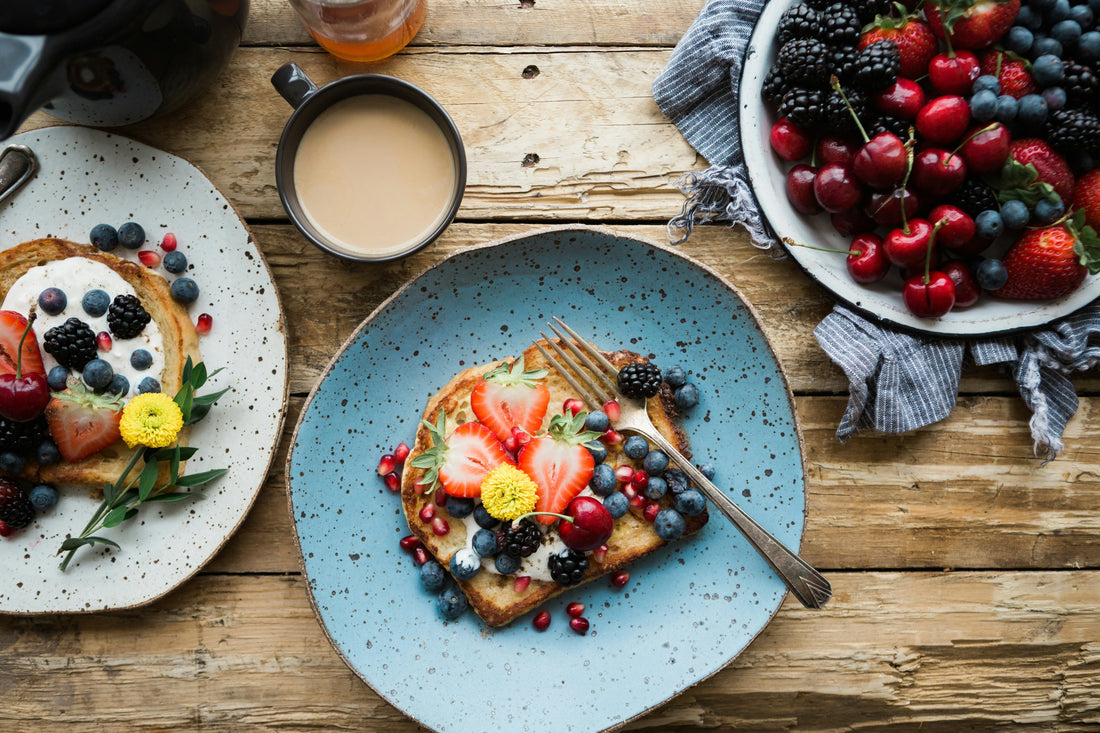 strawberries and blueberries on toast at a breakfast table